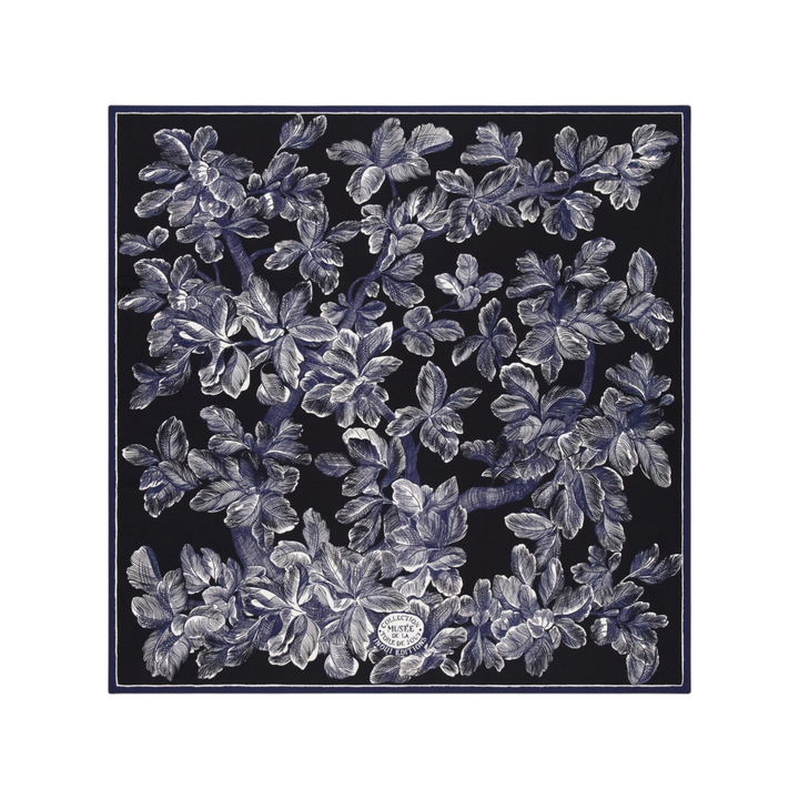 The Tiny Finch Square Arboris Blue wool scarf featuring a detailed white tree engraving on a dark blue background.
