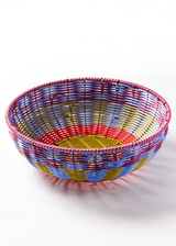 The Tiny Finch Maegen hand-woven polypropylene bowl in cornflower blue, yellow, and red with a textured rattan style.