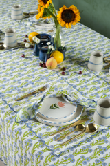 The Tiny Finch cotton placemat with blue floral blockprint and scalloped embroidered edges on a matching tablecloth.