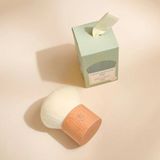 The Tiny Finch kabuki makeup brush with soft white synthetic bristles and a natural beechwood handle next to its box.