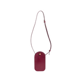 The Tiny Finch Segui Sumac leather sling bag in deep red with an adjustable strap and solid brass hardware closure.