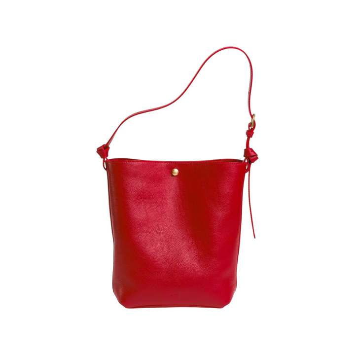 The Tiny Finch Lee Carmine bucket tote in red vegetable tanned leather with adjustable strap and brass hardware.