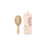 The Tiny Finch Care & Shine small hair brush with beechwood handle, boar bristles, and nylon pins next to its box.