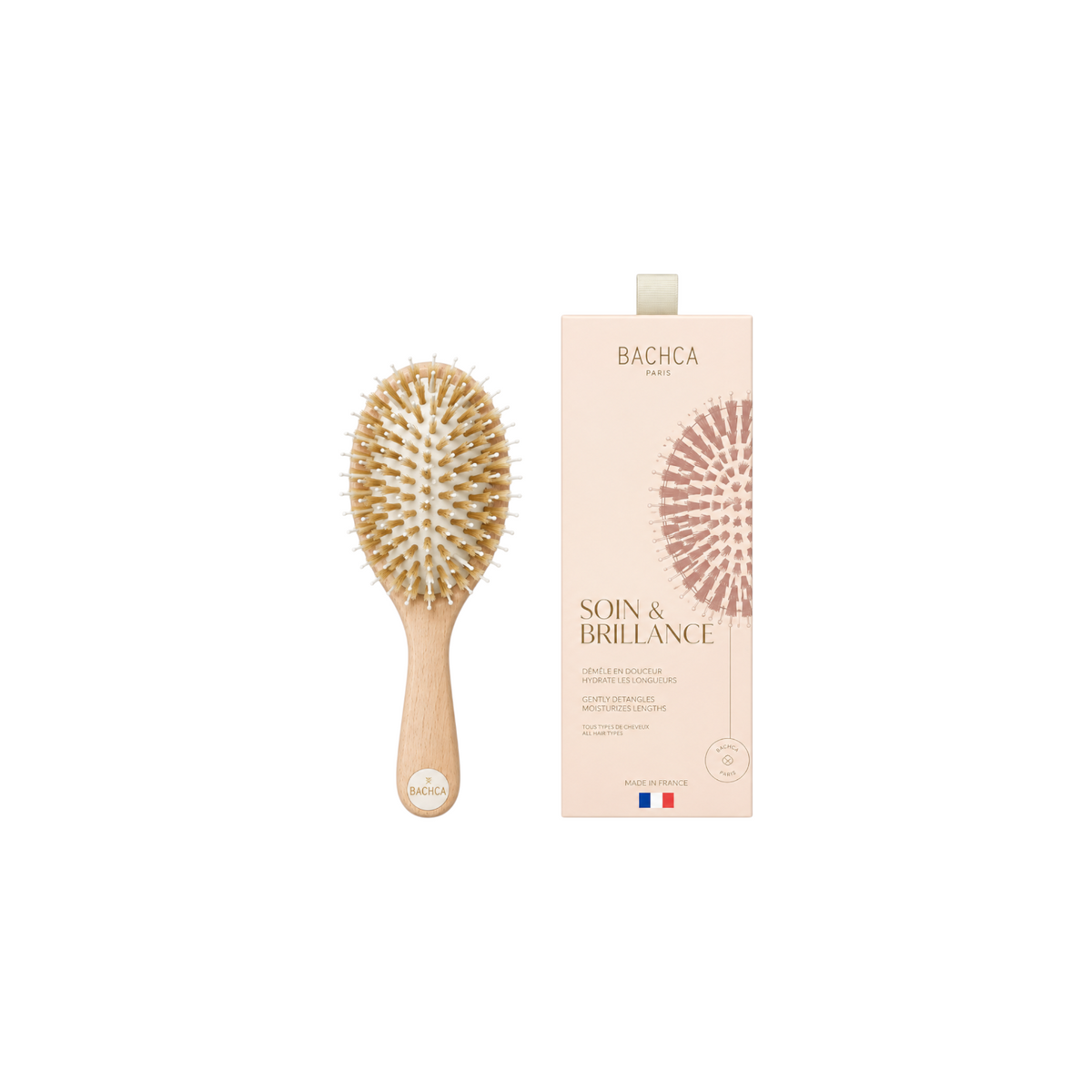 The Tiny Finch Care & Shine small hair brush with beechwood handle, boar bristles, and nylon pins next to its box.