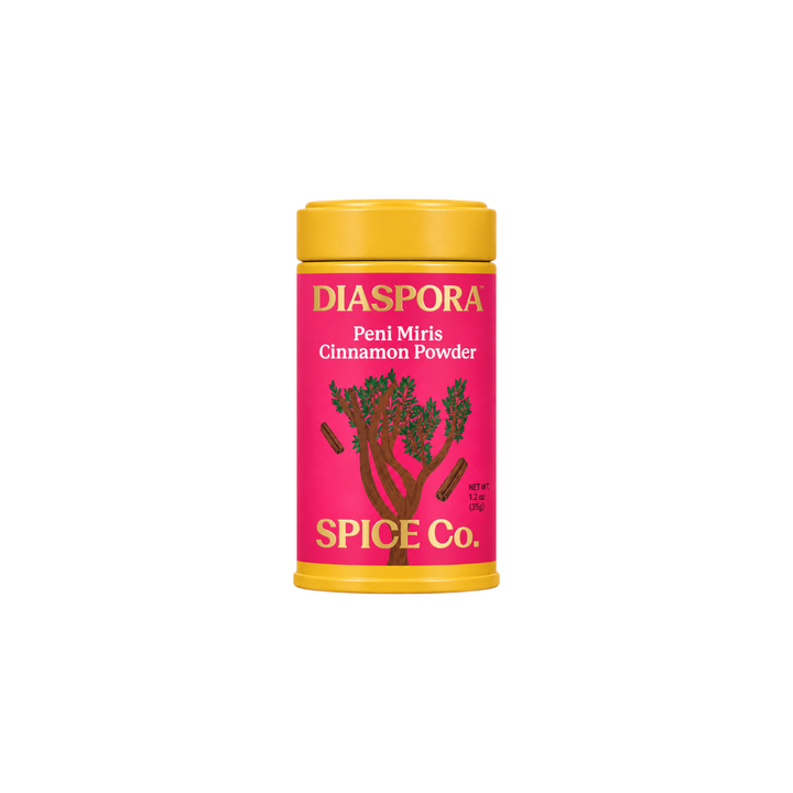 The Tiny Finch Diaspora Peni Miris Cinnamon Powder in a bright pink canister with yellow lid and tree illustration.