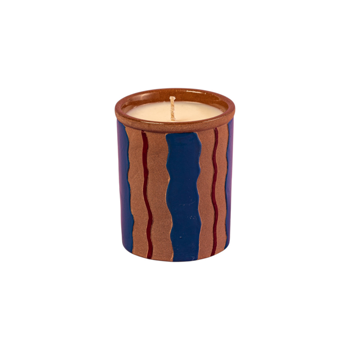 The Tiny Finch Maegen ceramic candle in a sand-textured pot with blue and brown wavy stripes and cedar scent.