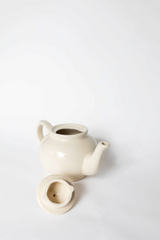 The Tiny Finch handmade cream stoneware teapot with a matching lid, featuring a durable lead-free ceramic design.