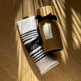 The Tiny Finch lavender eye pillow with black and white striped fabric next to its cylindrical gift packaging.