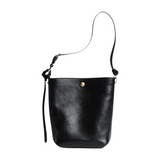 The Tiny Finch Lee black vegetable tanned leather bucket bag with adjustable strap and solid brass hardware