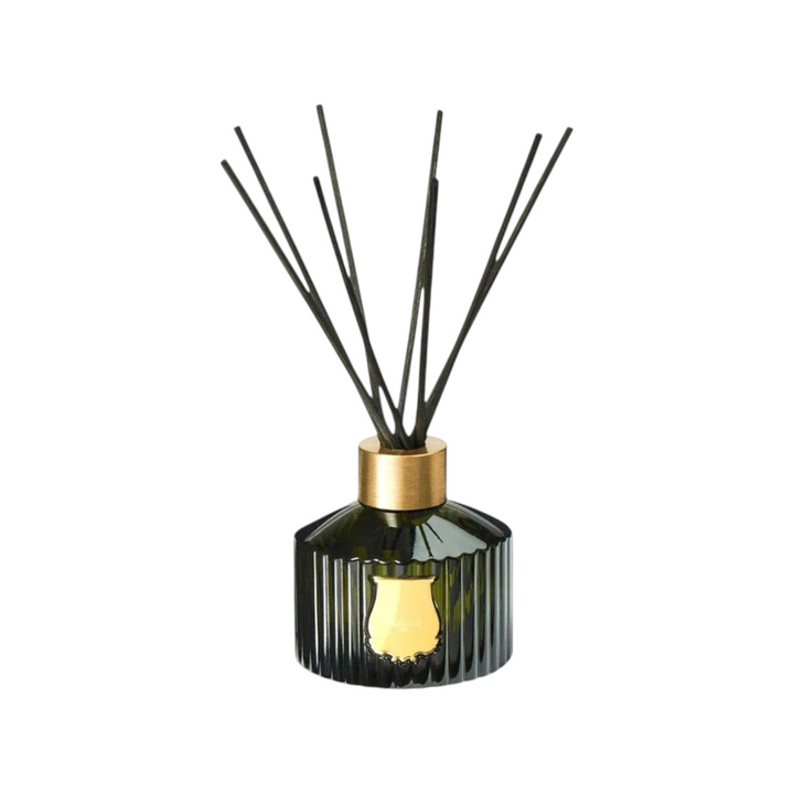The Tiny Finch Gabriel diffuser in a dark green ribbed glass bottle with a gold cap and black reed sticks.