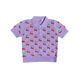 The Tiny Finch violet organic cotton polo shirt featuring a playful red cherry and green leaf knit pattern.