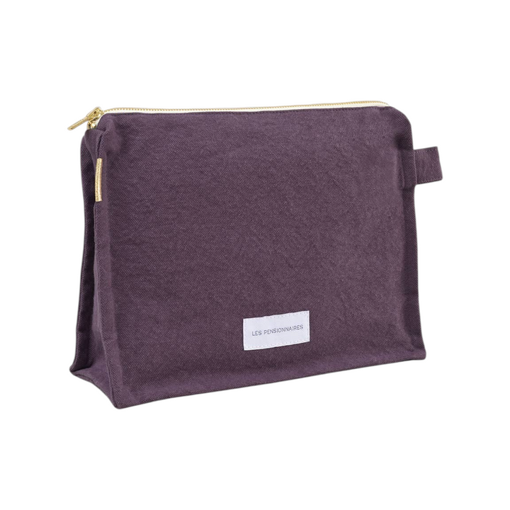 The Tiny Finch Les Pensionnaires eggplant purple organic cotton canvas toiletry bag with gold zipper and side tab.