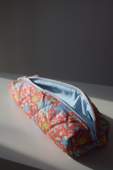 The Tiny Finch quilted hair tools bag in a floral persimmon print with a blue and white striped interior lining.