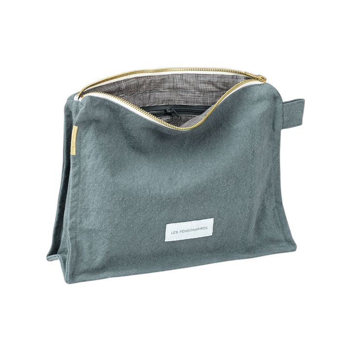 The Tiny Finch Horizon Blue organic cotton canvas toiletry bag with a gold zipper and checkered interior lining.