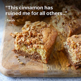 The Tiny Finch Peni Miris cinnamon powder used in a freshly baked golden brown streusel cake on a wooden board.