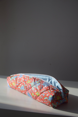 The Tiny Finch Persimmon hair tools bag in a quilted floral print with a blue and white striped interior lining.