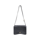 The Tiny Finch Val black leather crossbody bag with a minimalist flap design and a small gold hexagonal stud.