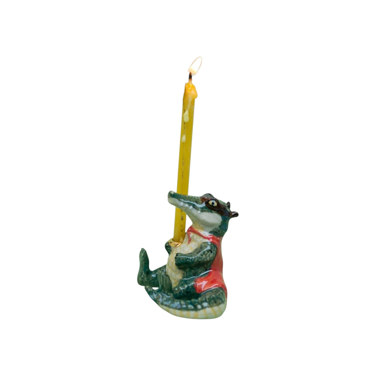The Tiny Finch porcelain alligator cake topper dressed as a bandit with a red cape holding a lit yellow candle