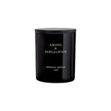 The Tiny Finch Amber & Sandalwood scented candle in a black hand-painted glass vase with a wooden lid.