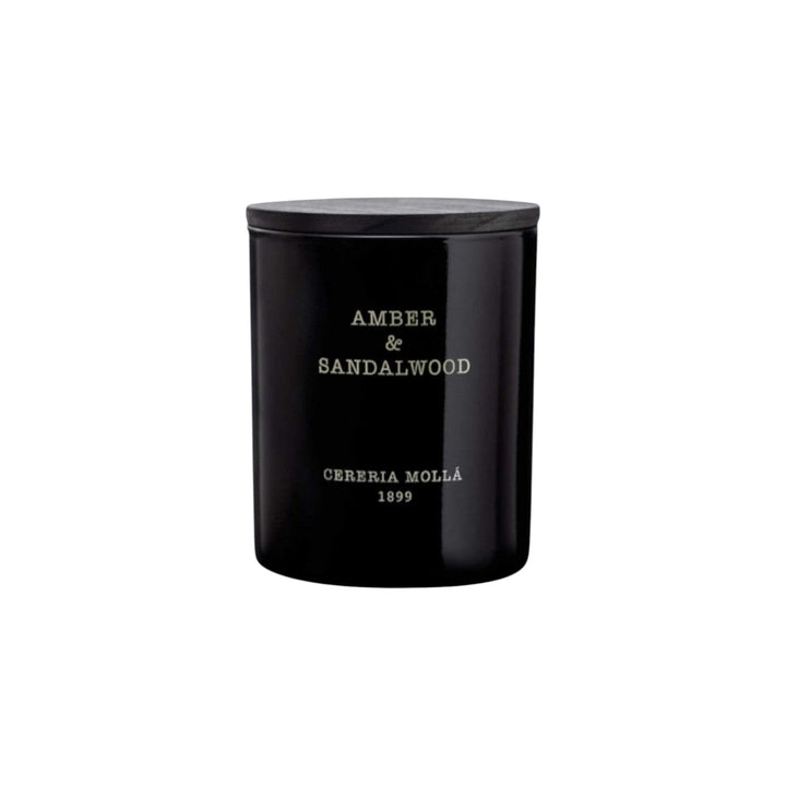 The Tiny Finch Amber & Sandalwood scented candle in a black hand-painted glass vase with a wooden lid.