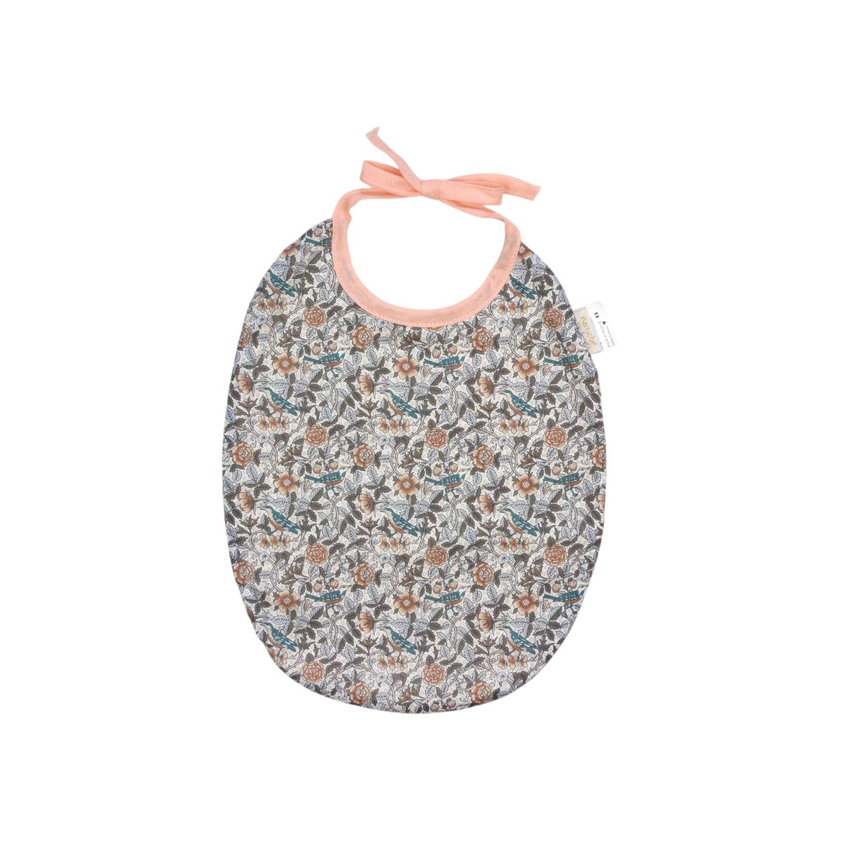 The Tiny Finch Bib Berenice featuring a delicate floral Liberty fabric pattern with peach-colored tie straps.
