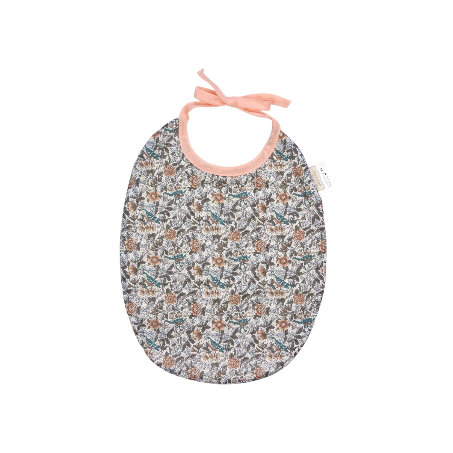 The Tiny Finch Bib Berenice featuring a delicate floral Liberty fabric pattern with peach-colored tie straps.