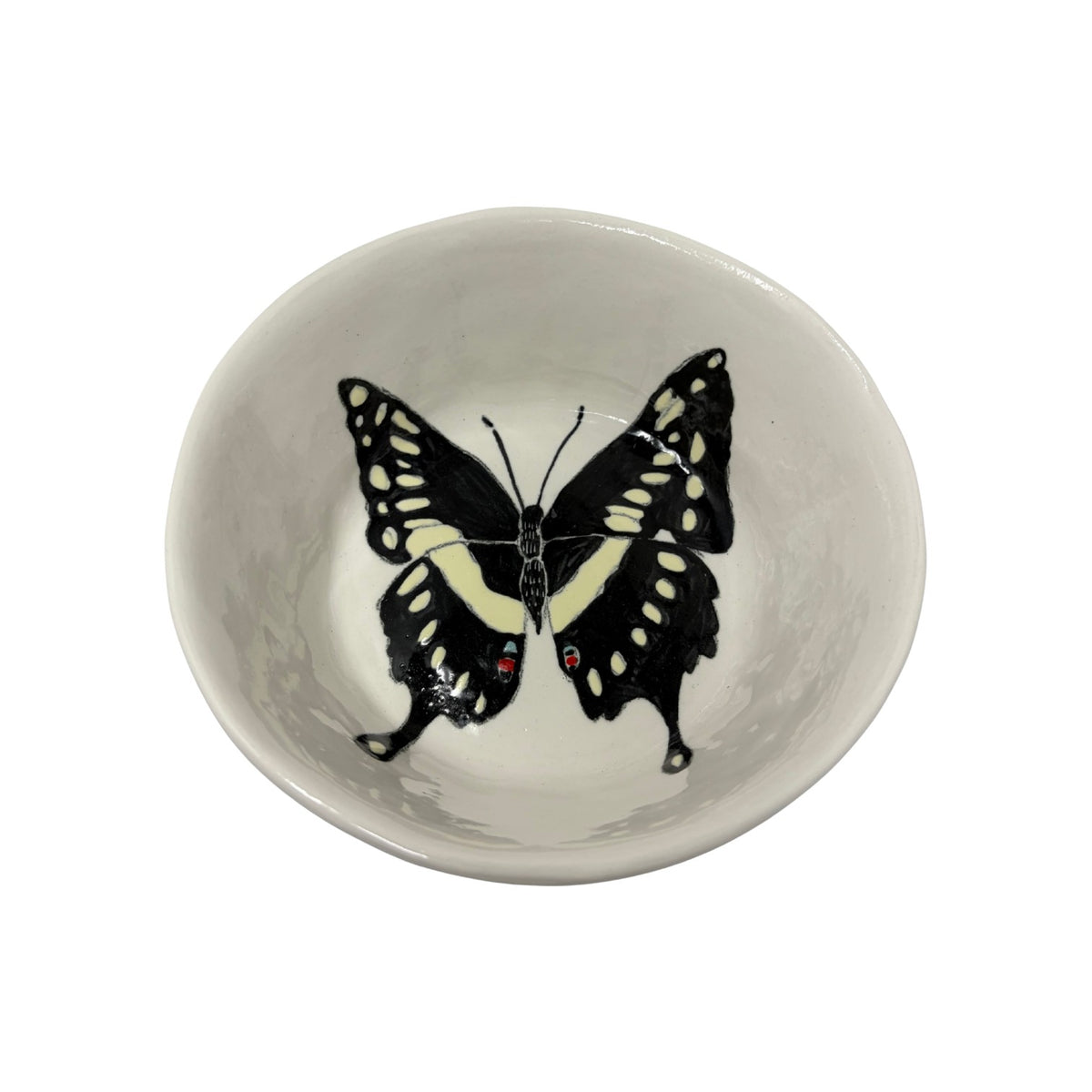 The Tiny Finch ceramic snack bowl featuring a hand-painted black and yellow butterfly design on a white background.