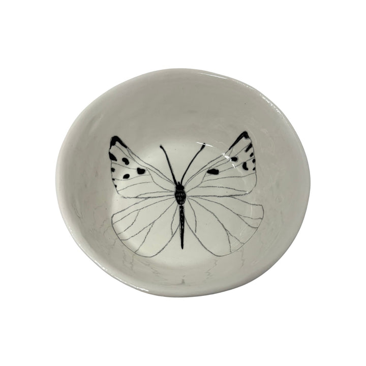 The Tiny Finch white ceramic snack bowl featuring a delicate black butterfly illustration on the interior base.