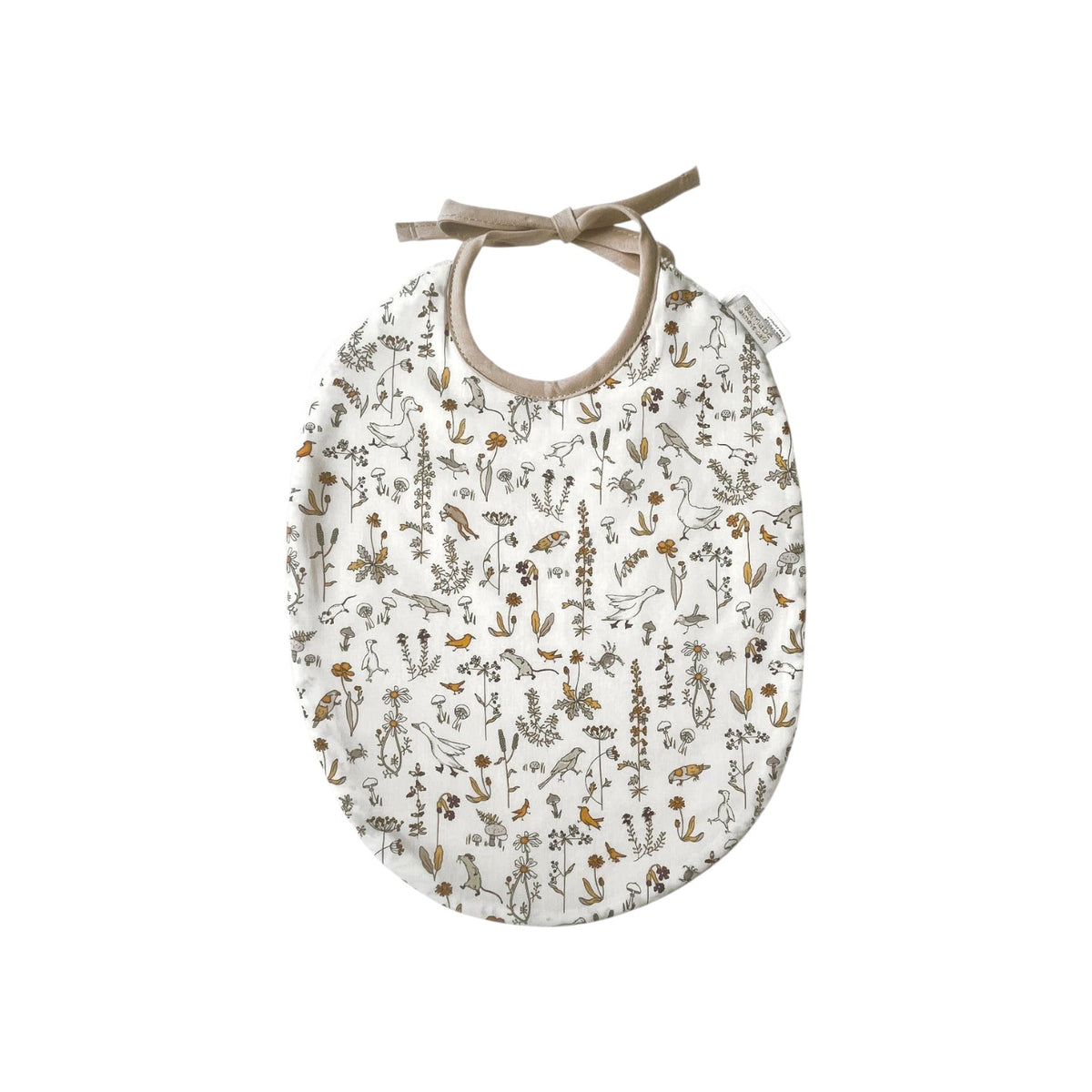 The Tiny Finch Camille baby bib in white Liberty fabric with delicate floral and animal print and tie closure