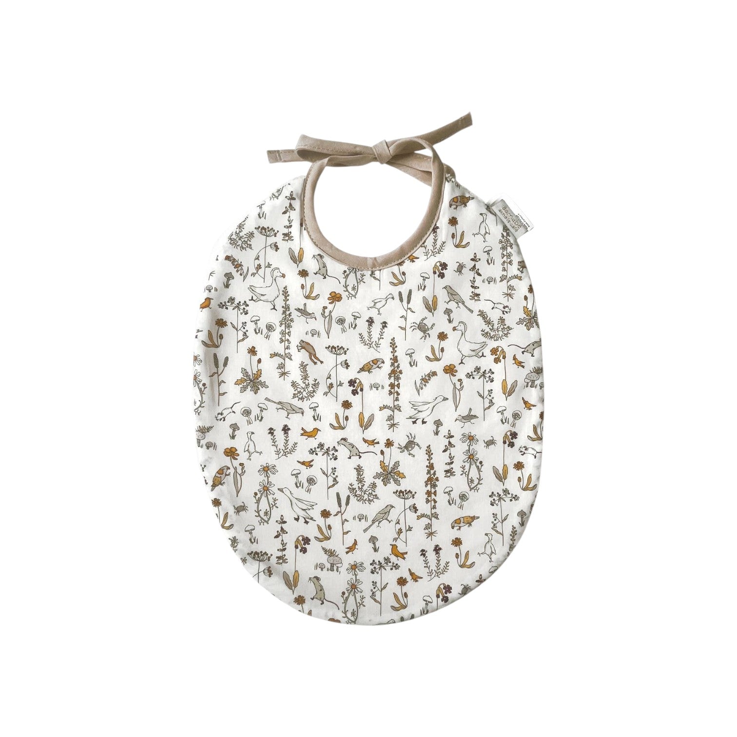 The Tiny Finch Camille baby bib in white Liberty fabric with delicate floral and animal print and tie closure