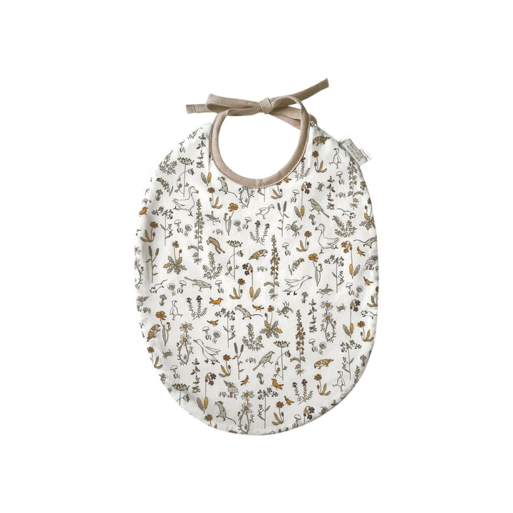 The Tiny Finch Camille baby bib in white Liberty fabric with delicate floral and animal print and tie closure