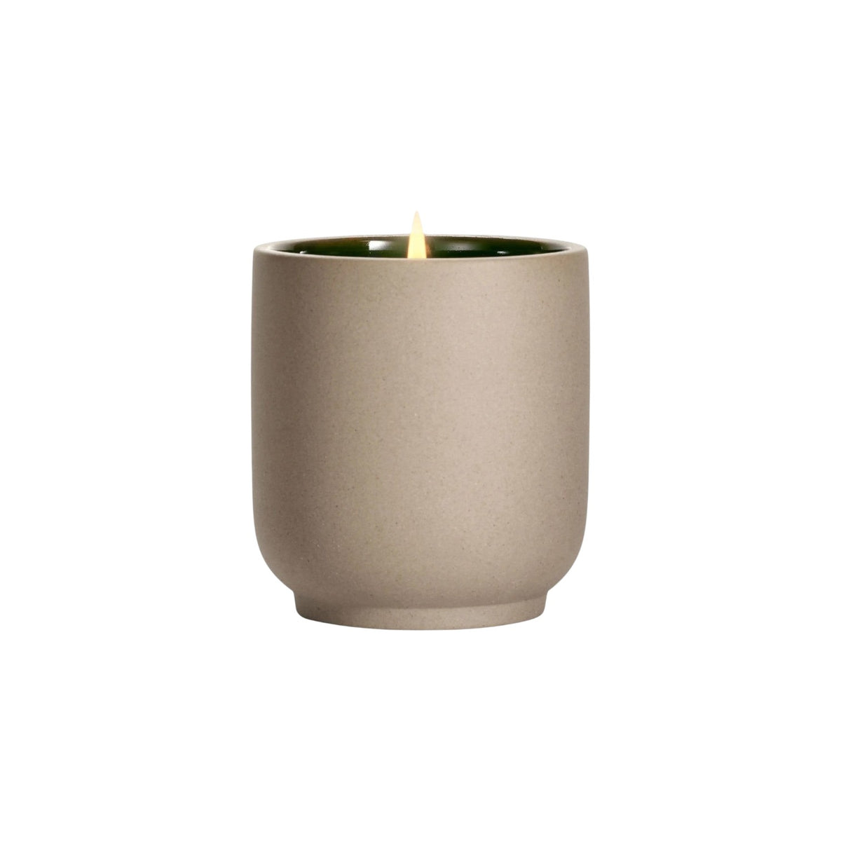 The Tiny Finch Cece candle in a beige kiln-fired ceramic vessel with a green interior and a lit organic cotton wick.