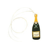 The Tiny Finch champagne bottle gift tag in natural white paper with gold foil accents and a white ribbon tie.