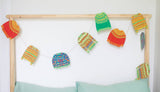 The Tiny Finch nine-foot Christmas garland featuring ten colorful, hand-printed recycled paper sweater ornaments.