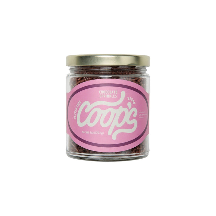The Tiny Finch Coop's chocolate sprinkles in a 6 oz glass jar with a pink label featuring white cursive text.