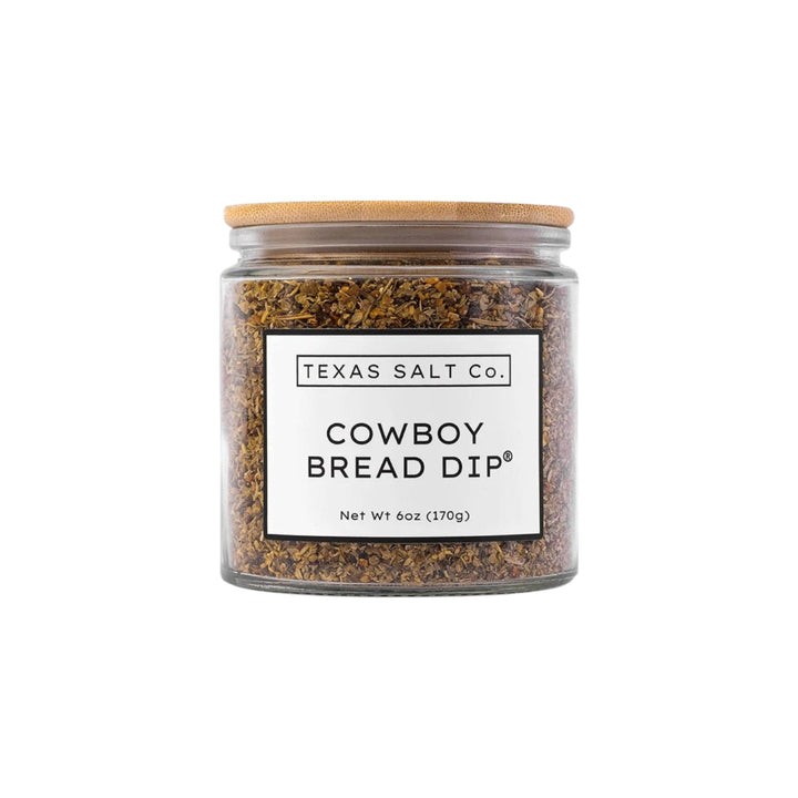 The Tiny Finch Cowboy Bread Dip by Texas Salt Co in a glass jar with a bamboo lid, featuring smoked herb seasoning.
