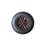 The Tiny Finch Original Drinking Chocolate star-shaped cacao disc served on a dark rustic ceramic plate