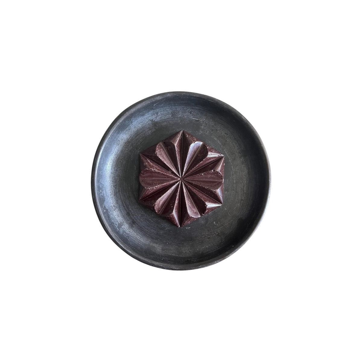 The Tiny Finch Original Drinking Chocolate star-shaped cacao disc served on a dark rustic ceramic plate