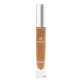 The Tiny Finch Macrene Actives high performance concealer in extra deep shade with a silver cap in a glass tube.