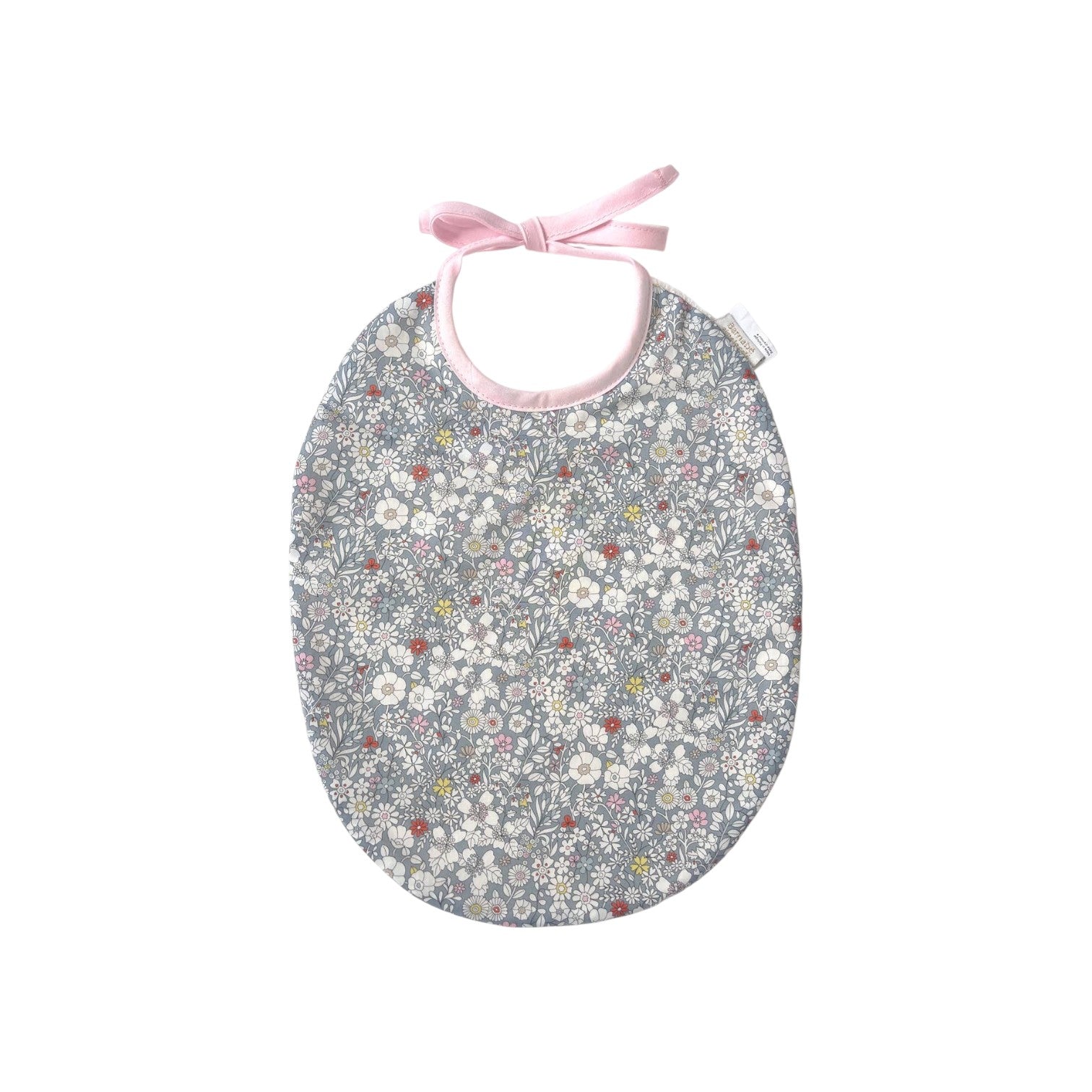 The Tiny Finch Bib Katie featuring a grey Liberty fabric with delicate floral patterns and soft pink tie closure.