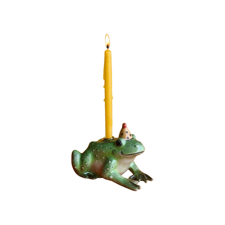 The Tiny Finch porcelain frog cake topper with a party hat holding a yellow taper candle