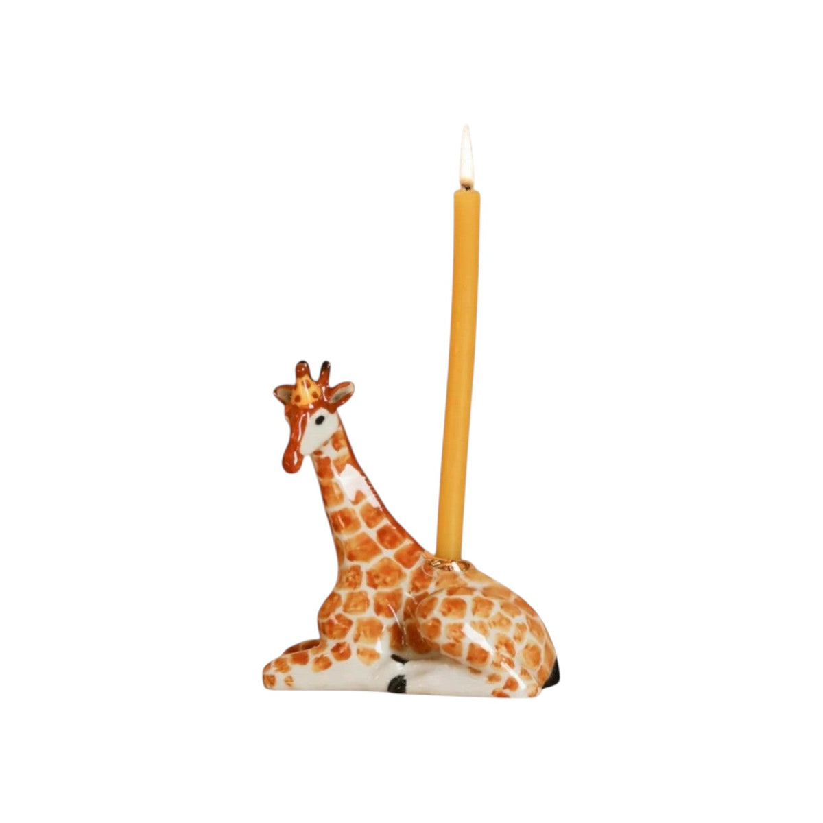 The Tiny Finch handcrafted giraffe cake topper with a lit yellow taper candle, featuring hand-painted brown spots.