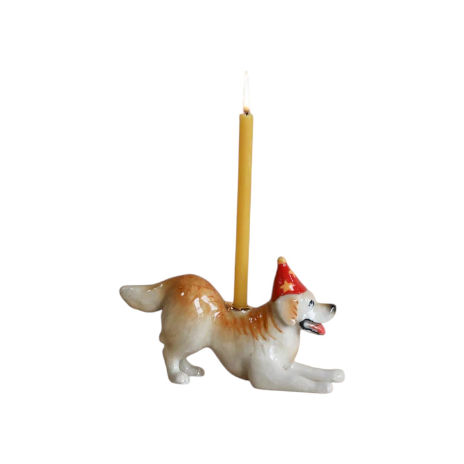 The Tiny Finch porcelain Golden Retriever cake topper wearing a red party hat with a lit yellow birthday candle.