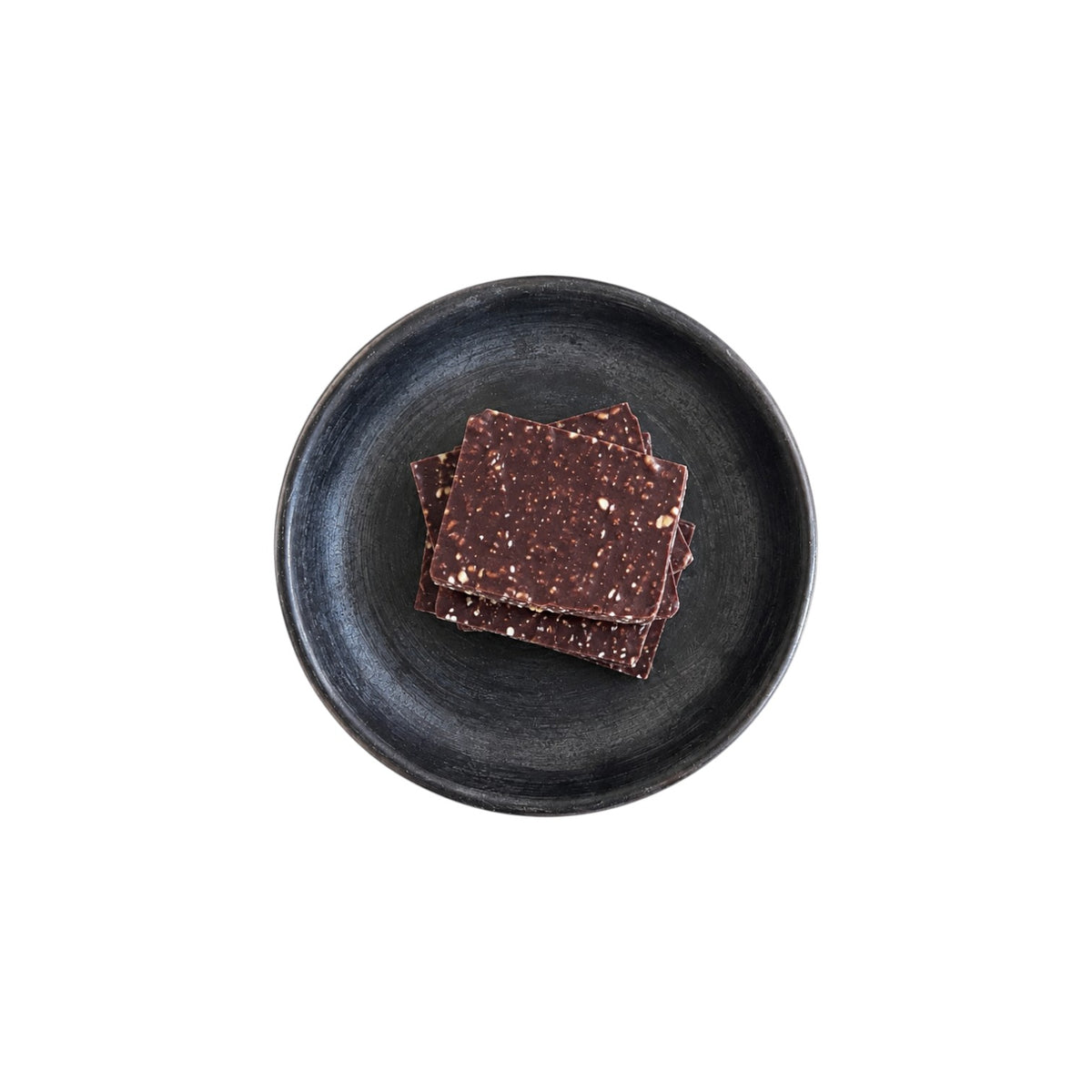 The Tiny Finch Hazelnut and Mexican Cinnamon Bark pieces with puffed quinoa on a dark textured ceramic plate.