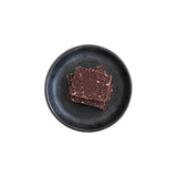 The Tiny Finch Hazelnut and Mexican Cinnamon Bark pieces with puffed quinoa on a dark textured ceramic plate.