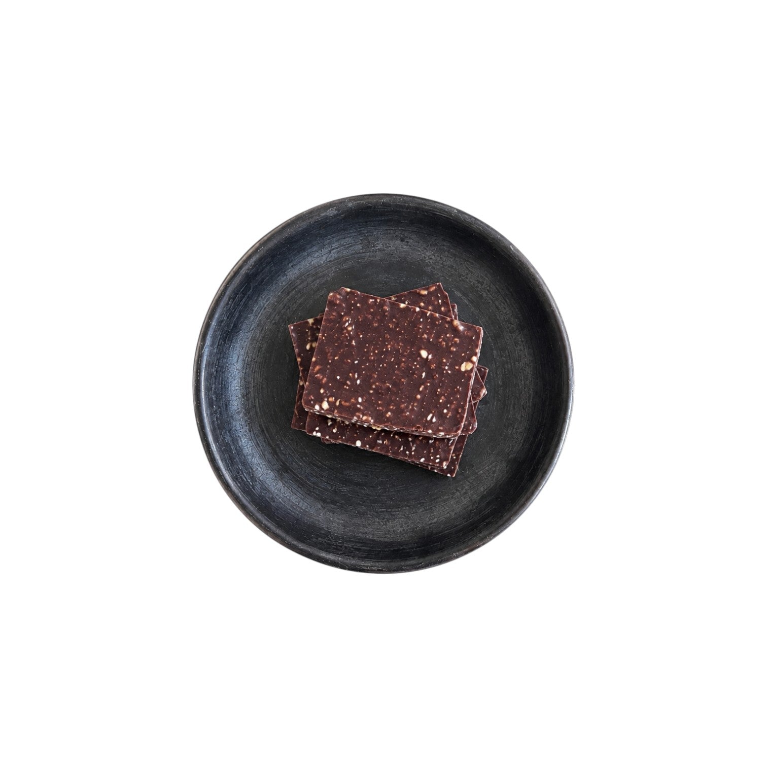 The Tiny Finch Hazelnut and Mexican Cinnamon Bark pieces with puffed quinoa on a dark textured ceramic plate.