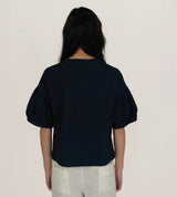 Back view of The Tiny Finch Intention Top in indigo blue with relaxed fit, crew neck, and gathered puff sleeves.