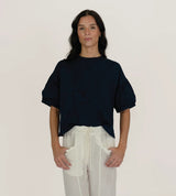 Model wearing The Tiny Finch Intention Top in indigo with a crew neckline and gathered puff sleeves.