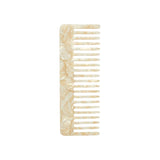The Tiny Finch ivory wide-tooth comb handcrafted from renewable Italian acetate with a marbled finish.