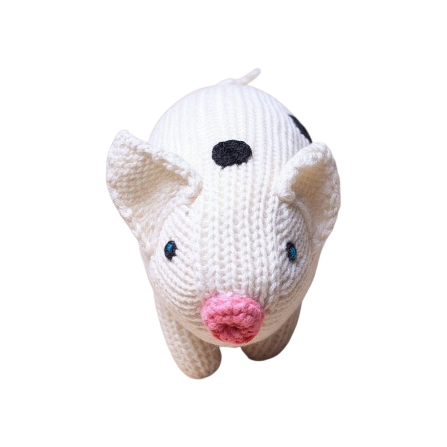 The Tiny Finch handmade white knitted baby pig rattle with black spots and a pink snout, viewed from above.
